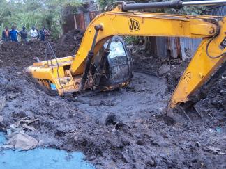 Image of excavator immersed in mud digging it’s way out.